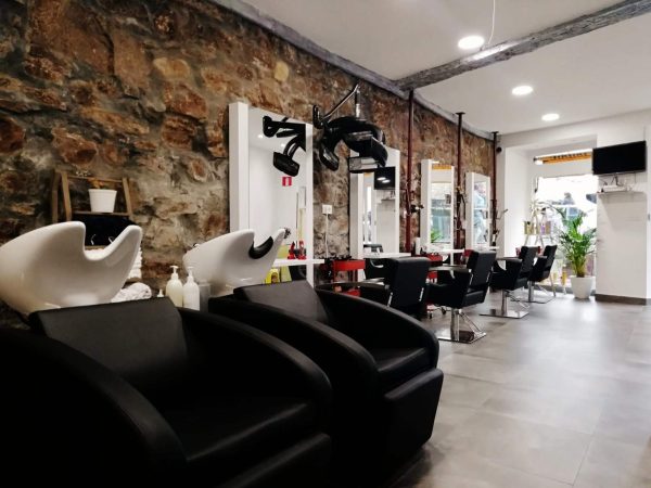 Peluquería con lavacabezas negros y pared de piedra vista
