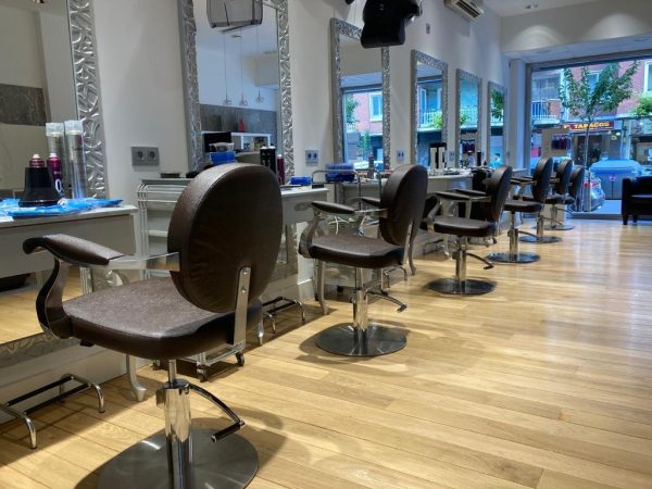 Salón de peluquería con sillones, espejos de marco plateado y suelo de madera