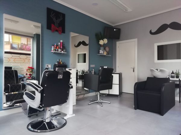 Barbería con sillón de barbero, pared azul y detalles decorativos de bigotes