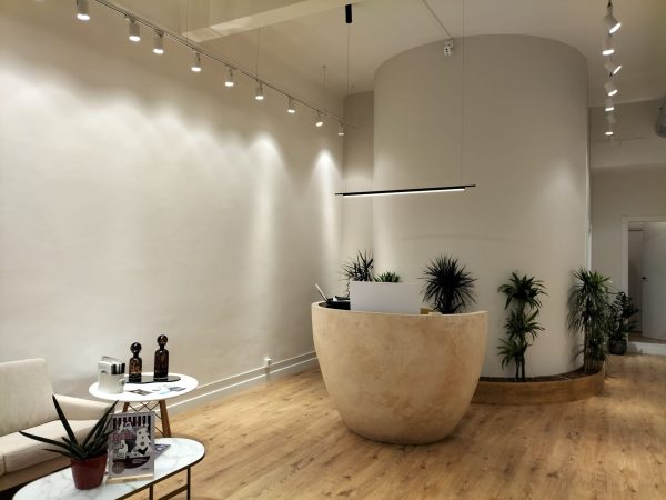 Recepción de un local comercial con mostrador curvo de madera, paredes blancas y plantas