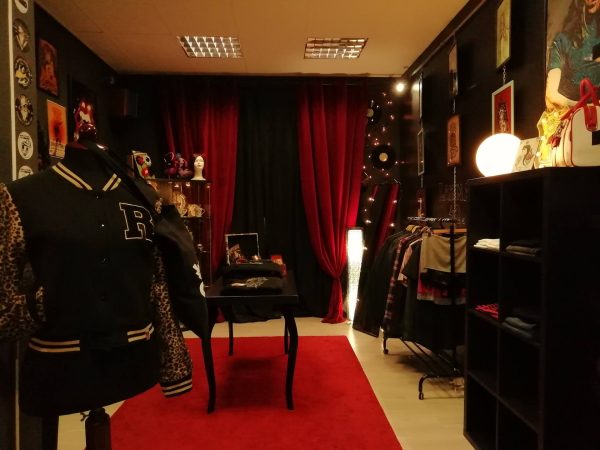 Tienda de moda con paredes oscuras, cortinas rojas y alfombra roja
