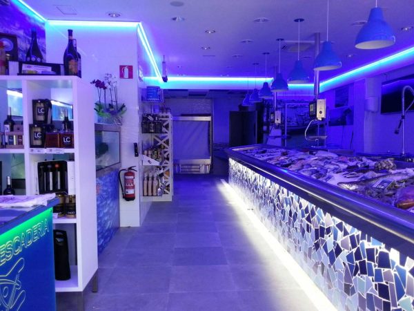 Pescadería con mostrador de mosaico iluminado y luz azul en el techo